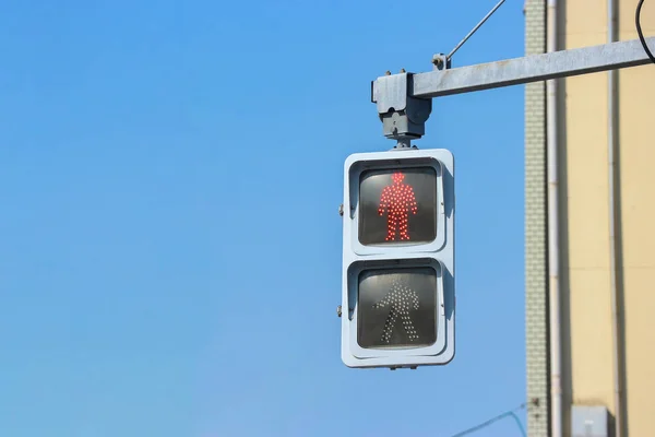urban red traffic light for pedestrians to stop for waiting for green light with blue sky as background.