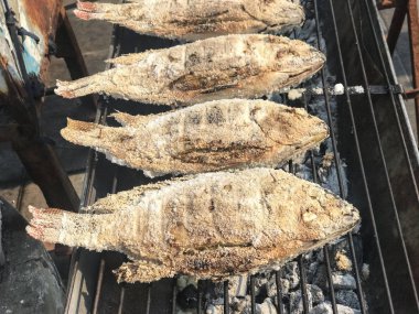 Tilapia balığını kömür arka planında kızartıyorum..