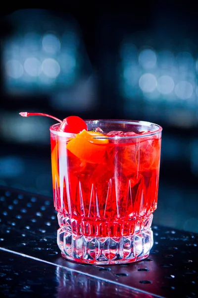 Червоний коктейль у скляній банці, вишня та апельсинова шкірка на столі — стокове фото
