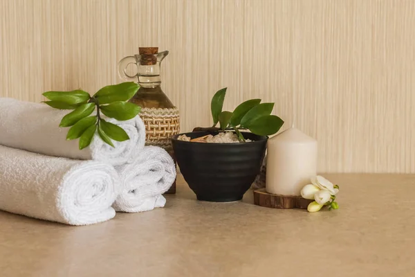 Spa, güzellik ve sağlıklı yaşam arka plan. Havlu, kozmetik masaj yağı, yaprak, çiçek, kabukları ve mum ile deniz tuzu