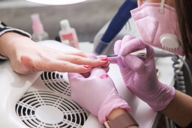 Jel cilası tasarımı. Salondaki kadın usta müşterinin ellerinde fırçayla resim yapıyor. Güzellik endüstrisi, yaratıcılık konsepti.