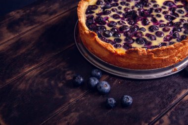 Ahşap bir zemin ve bir buket kurutulmuş lavanta ile ekşi kremalı yaban mersinli rostat turtası. Kapat.