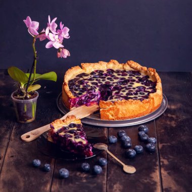 Ekşi kremalı yaban mersinli Rustik kurabiye turtası ahşap arka planda ve falaenopsis çiçeğiyle doluyor. Kapat..