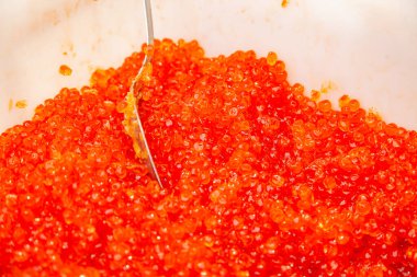Plastik kovada kaşıkla somon kırmızısı havyar. Deniz ürünleri. Rus kırsal fuarında denizden pahalı bir şarküteri..