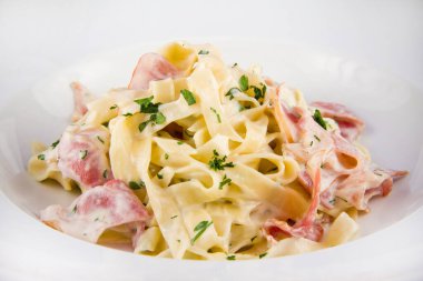 Pastırmalı ve fesleğenli Carbonara makarnası. Beyaz bir tabakta yaklaş..