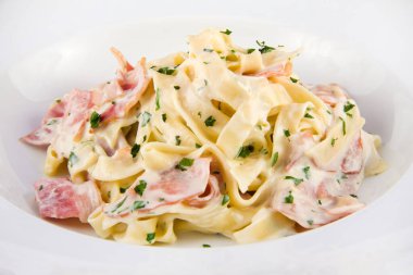 Pastırmalı ve fesleğenli Carbonara makarnası. Beyaz bir tabakta yaklaş..