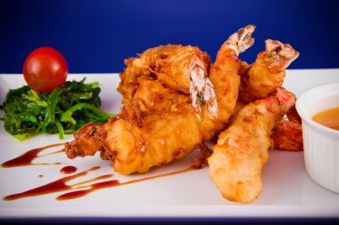 Yağda kızartılmış kaplan karidesleri tatlı ve ekşi sosla servis edilir, Norveç yosunu ve dikdörtgen bir tabakta kiraz domatesleri..