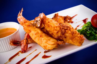 Yağda kızartılmış kaplan karidesleri tatlı ve ekşi sosla servis edilir, Norveç yosunu ve dikdörtgen bir tabakta kiraz domatesleri..