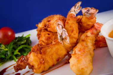 Yağda kızartılmış kaplan karidesleri tatlı ve ekşi sosla servis edilir, Norveç yosunu ve dikdörtgen bir tabakta kiraz domatesleri..