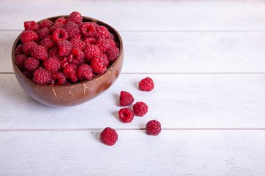 Beyaz ahşap arka planda hindistan cevizi kabuğunda ahududu..