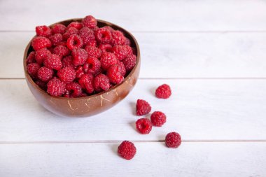 Beyaz ahşap arka planda hindistan cevizi kabuğunda ahududu..