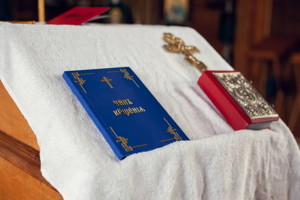 The sacrament of baptism in the Orthodox Church. Prayer books and a crucifix on the table. Inscription on the book: the rite of baptism.