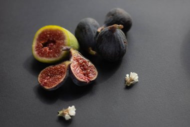 Koyu arkaplanda beyaz çiçekli bir grup yeşil ve mavi incir