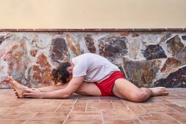 Kaslı genç adam evde geriniyor. Ev işi konsepti ve sağlıklı yaşam.