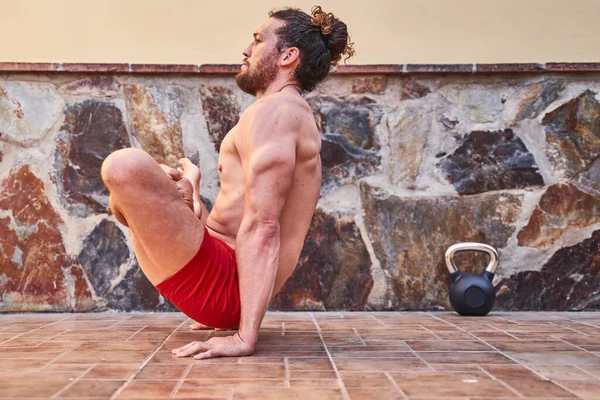 Young muscular man doing yoga exercise at home. Home training concept and healthy living.