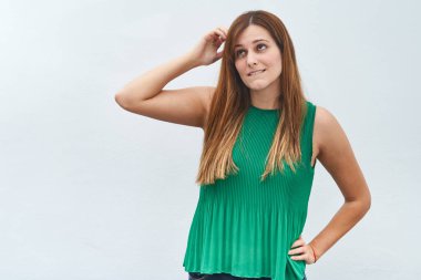 Genç bir kadın, beyaz bir arka planda izole edilmiş bir şekilde düşünme jesti yapıyor..