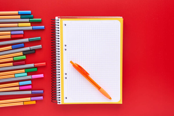 Цветные маркеры и блокнот на красном фоне. Возвращение к школьной концепции и сумасбродству
.