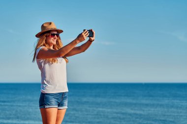 Yazın deniz kenarında şapka takan genç bir kadın. Seyahat, tatil ve macera kavramı.