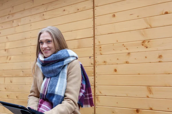 Tablet açık tutan sarışın güzel kadın. Tartan eşarp ahşap duvar önünde ve tablet kullanarak genç kadın portresi. 