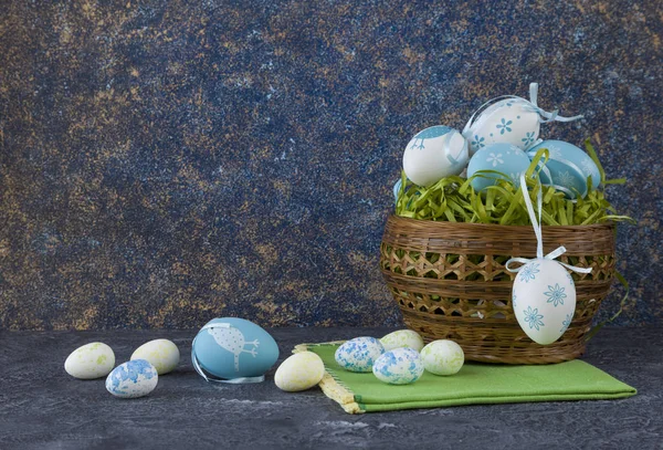 Easter basket with coloured Easter eggs on dark stone table