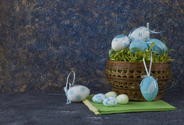 Easter basket with coloured Easter eggs on dark stone table