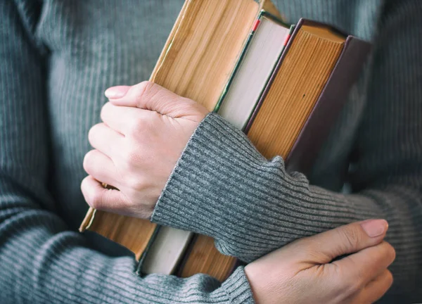 Gri giysili kadın üç kitap elinde tutan.