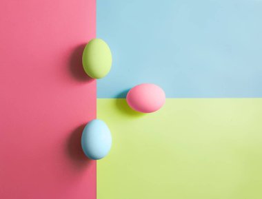 Üç renkli arka plan üzerinde renkli yumurta. 