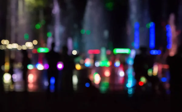 La fuente de la ciudad con iluminación de color en la noche fuera de foco . — Foto de Stock