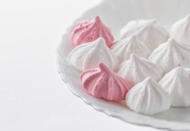 Beyaz-pembe meringues beyaz bir arka plan üzerinde beyaz bir plaka üzerinde. 