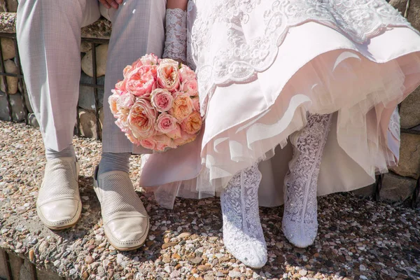 Feet of bride and groom, wedding shoes. A wedding bouquet from pink roses.