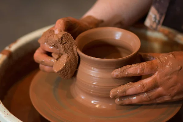 Rueda giratoria de alfarero y vajilla de arcilla en ella tomada desde arriba. Un esculpe sus manos con una taza de barro en la rueda de un alfarero. Manos en arcilla . — Foto de Stock