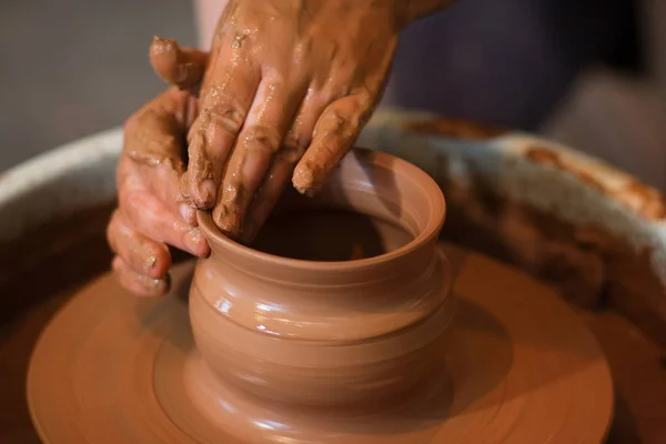 Obrotowe koło garncarskie i gliniane naczynia na nim robione z góry. A rzeźbi ręce z gliny cup na koło garncarskie. Ręce w glinie. — Zdjęcie stockowe