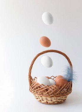 Paskalya kompozisyon. Bir sepete düşen doğal renk yumurtaları. Beyaz bir arka planda. Mutlu Paskalya. 