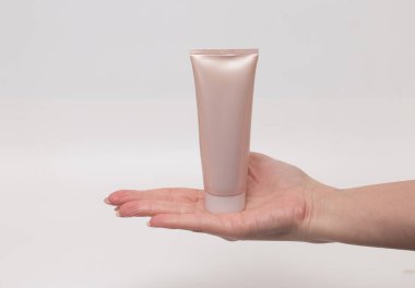 Kadın el bir krem tüp tutan, beyaz arka plan. Cilt bakım ürünü. Sağlık ve güzellik konsepti. Ön görünüm. 