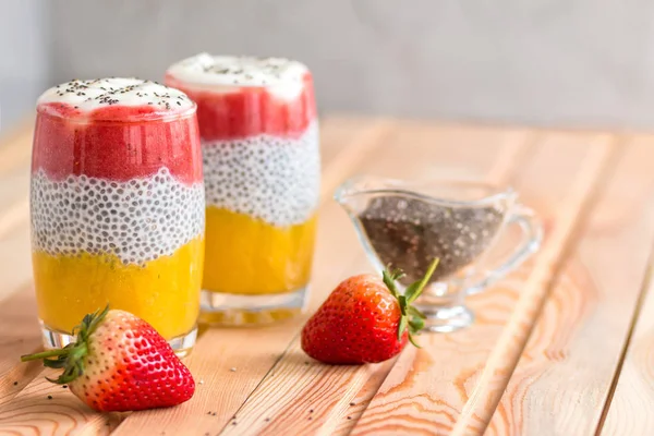 Mango ile Chia puding, Doğal yoğurt, Chia, ahşap bir masada bir bardak vahşi çilek. Sağlıklı tatlı, süper gıda 