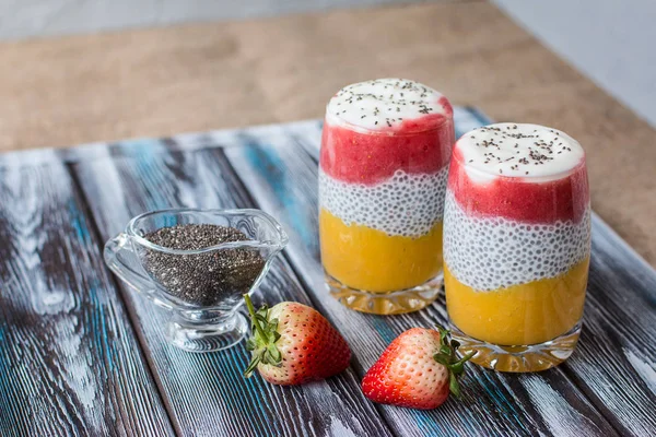 Mango ile Chia puding, Doğal yoğurt, Chia, ahşap bir masada bir bardak vahşi çilek. Sağlıklı tatlı, süper gıda 