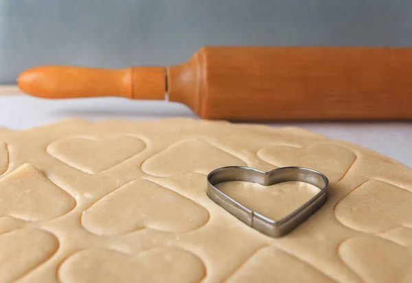 The process of baking cookies at home.Heart shaped cookie cutters cutting out holiday sugar cookies. St. Valentines Day. Side view — Stock Photo, Image