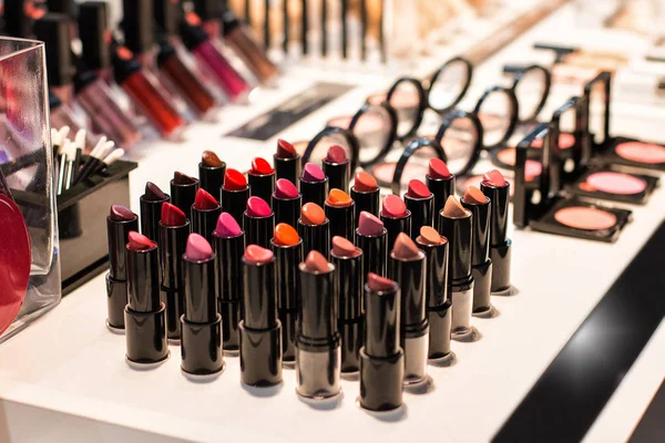 Different colors of lipstick and eye shadow on the shop window in the cosmetic store. Test sample. Front view — Stock Photo, Image