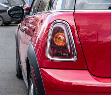 Kırmızı mini Cooper'ın arkası ve yüzü. Sokağa park etmiş kırmızı bir Mini Cooper'ın arka farı. 