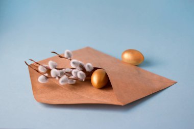 Altın ve gümüş Paskalya yumurtaları mavi bir arka plan üzerinde bir posta zarf içinde bir söğüt dalları ile. Paskalya konsepti. Kopya alanı. Ön görünüm