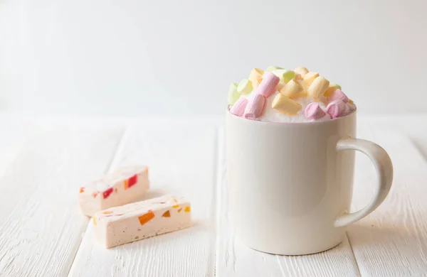 Šálek kávy se sladkou suflí s kousky a Marshmallow na bílém stole. — Stock fotografie