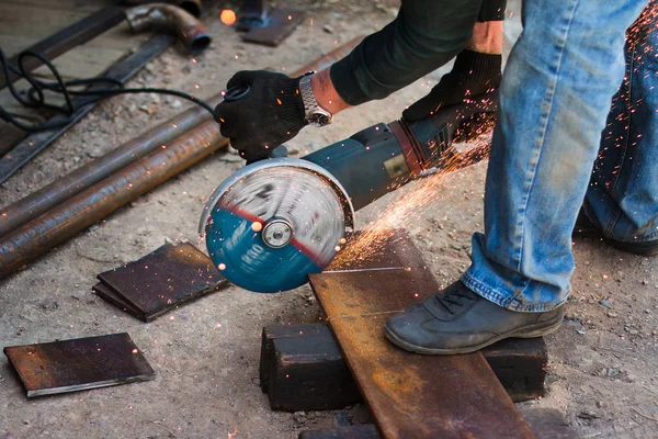 Manos de hombre con herramienta de corte de acero. El trabajador afuera, corta la lámina de metal. Sierra eléctrica que genera chispas calientes . —  Fotos de Stock