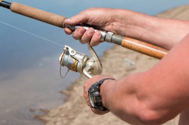 Nehri üzerinde bir iplik ile balıkçılık. Bir el ve iplik makarası balık, yakın bir adam yakalar