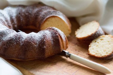 Yuvarlak tatlı kek bir bıçak ile ahşap bir tahta üzerinde pudra şekeri ile strewed. 