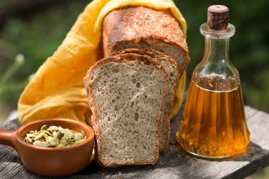 Ev yapımı taze ekmek, ayçiçeği yağı ile şişe, eski bir ahşap tahta üzerinde kabak ayçiçeği tohumu. 