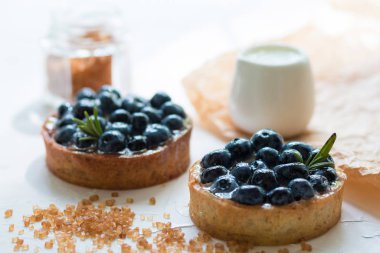 Beyaz masada kahverengi şeker ile taze yaban mersini ile Tartalets. Ön Görünüm