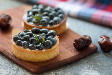 Kurutulmuş hurma ve damalı peçete ile ahşap tahta üzerinde yaban mersini ile Tartlets. Ön görünüm