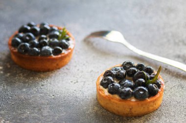 Hafif arka planda bir çatal ile vanilyalı muhallebi krem ile Lezzetli yaban mersini tartlets. Ön görünüm. 