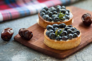 Kurutulmuş hurma ve damalı peçete ile ahşap tahta üzerinde yaban mersini ile Tartlets. Ön görünüm