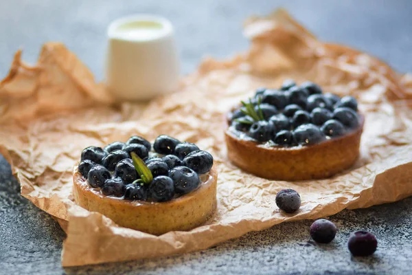 Gri bir yüzey üzerinde buruşuk kağıt üzerinde taze çilek ile Tartaletler. 